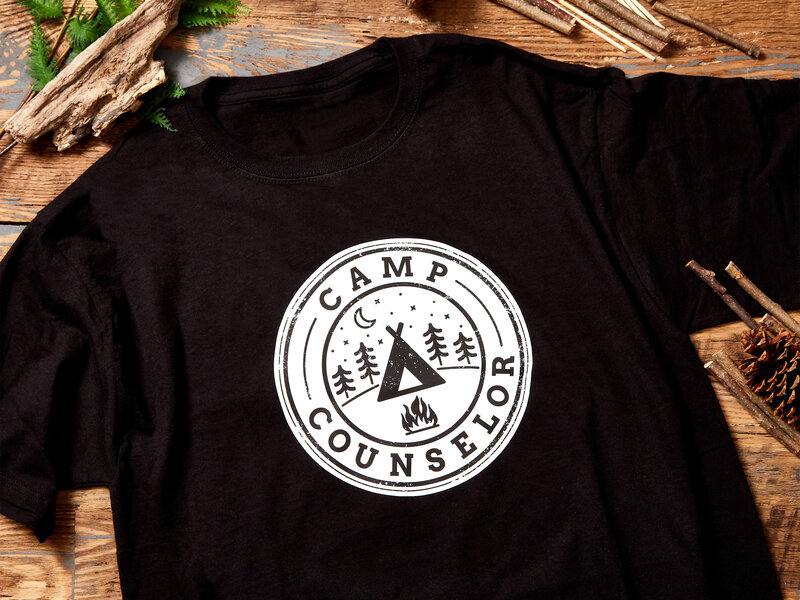 A black t-shirt with a white camp counselor logo on it
